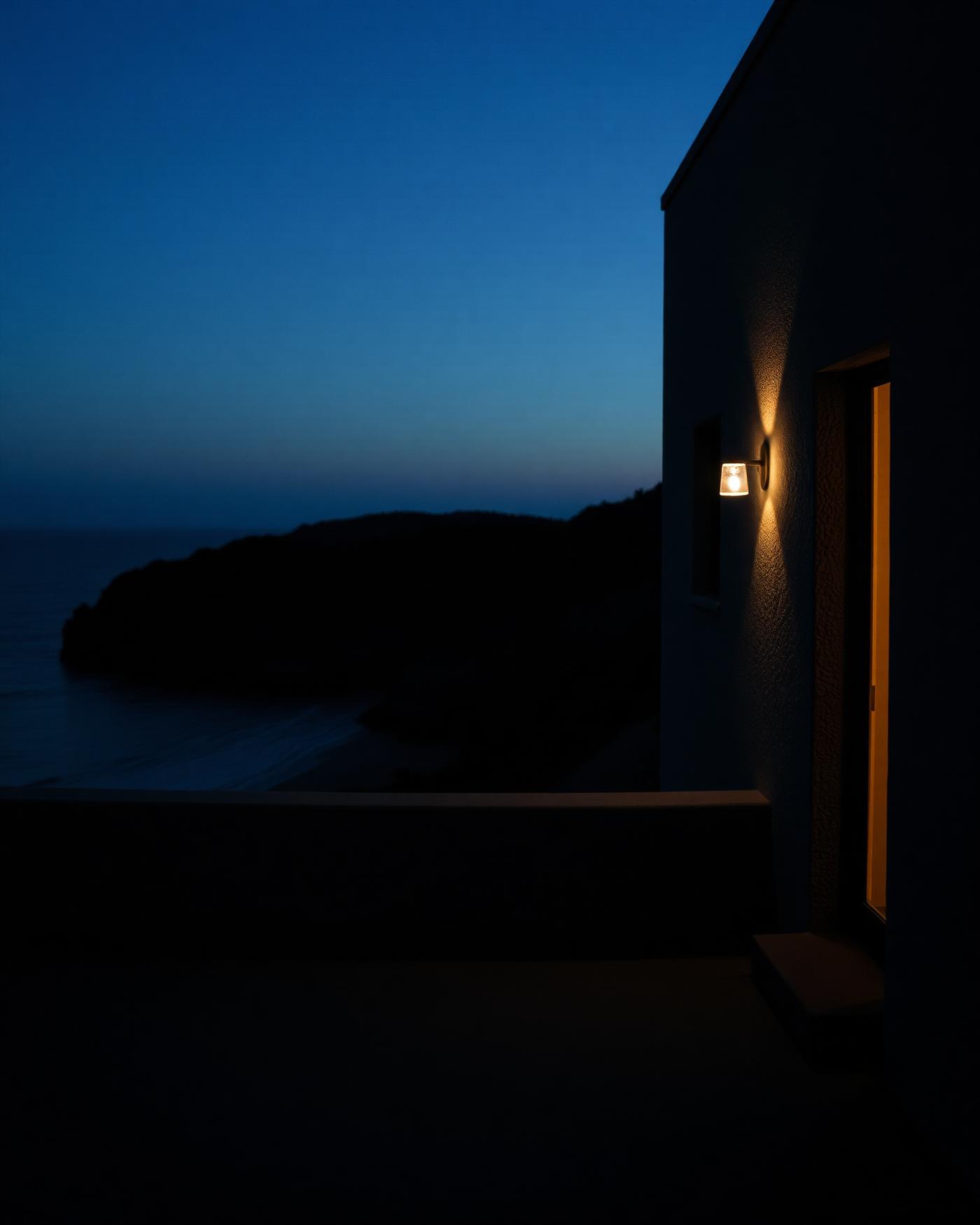 Coastal architecture at dusk, single warm light against a dark sea